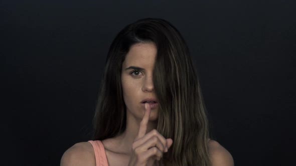 Woman holding finger to lips in silence alt