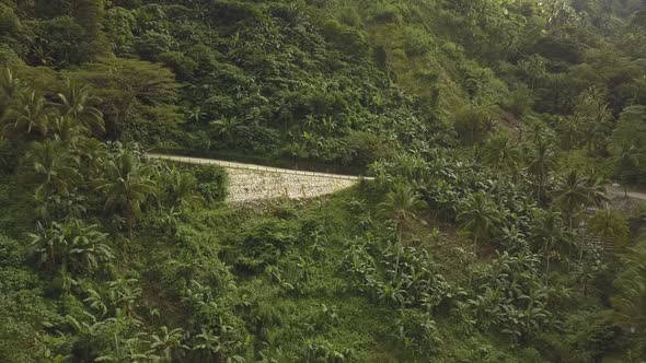 Man Riding a Motorcycle on a Road with Mountains in the Background alt