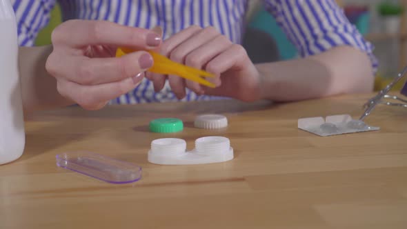 Young Woman's Hands Take Contact Lenses Out of the Container alt