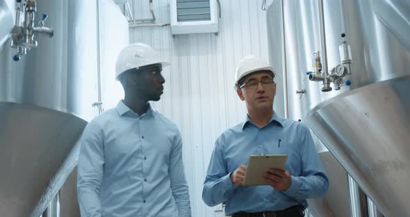 Two Industry Engineers Walk in Factory Use Tablet and Discuss Work alt