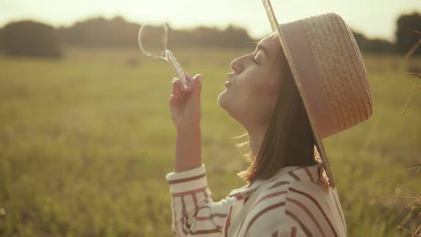 Young woman in hat blowing soap bubbles