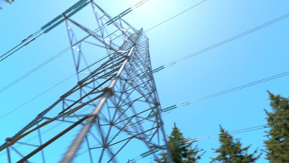 High voltage electricity pylons in a mountain forest. Blue sky in background. 4k alt