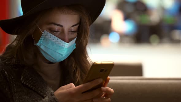 Close Up Woman in Protective Medical Mask Standing Using Smartphone on City Street with Bokeh Lights alt
