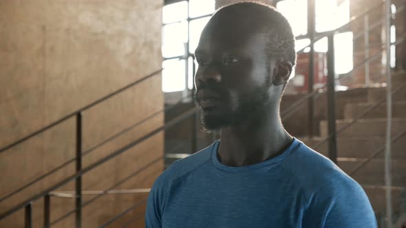 Portrait of black man in blue t-shirt looking at camera indoors alt