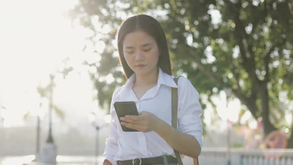 A beautiful Asian businesswoman in a white shirt is using a smartphone texting. alt