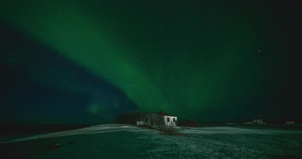 Timelapse of Aurora Borealis Northern Lights Over Small Building in the Show Field. Iceland
