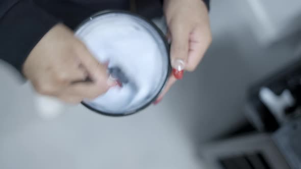 Above Shot of Hands Mixing Bleach Preparation for Hair Dye in Plastic Bowl alt