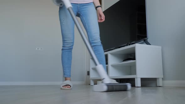 Woman Cleaning Living Room with Modern White Upright Vacuum Cleaner
