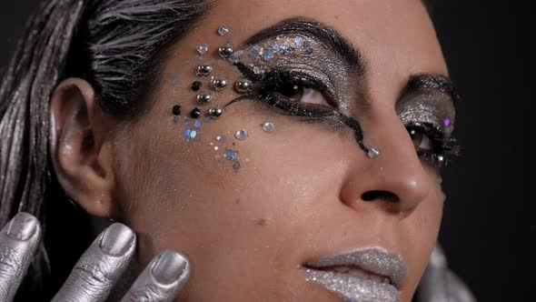Closeup of a Woman's Face with Bright Makeup Silver Lipstick and Hands alt
