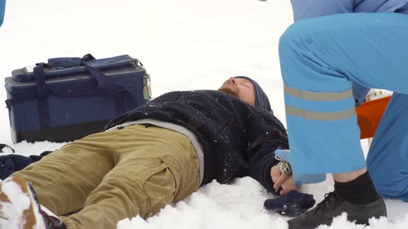 Paramedic Checking Pulse of Unconscious Patient alt