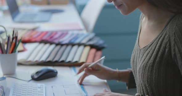 Interior designer sitting at desk and working on a house plan, she is drawing and using a ruler