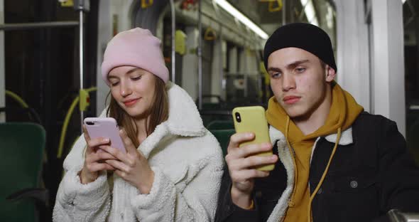 Young Couple Using Their Smartphones While Sitting on Seats in Public Transport. Good Looking Guy alt