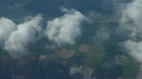 Filming From the Height of an Airplane of Multicolored Fields Through the Clouds