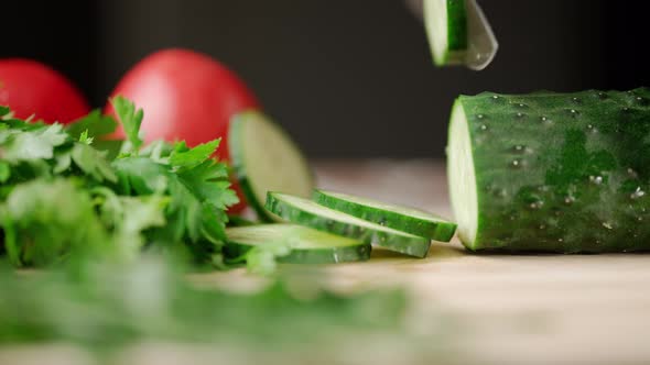 A Man Hands are Cutting a Ripe Green Cucumber alt