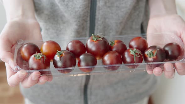 Organic Black Cocktail Tomatoes in a Plastic Box on a White Background