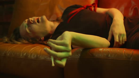 Drug Addict Sitting on Couch After Shooting Up with Heroin alt
