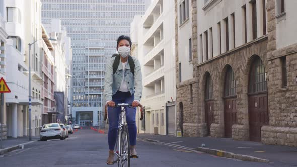 Woman riding on her bike while wearing medical coronavirus mask alt