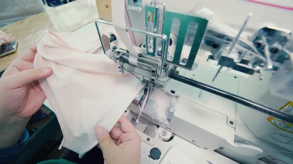 A Worker Is Sewing and Cutting Pieces of Fabric with a Sewing Machine alt