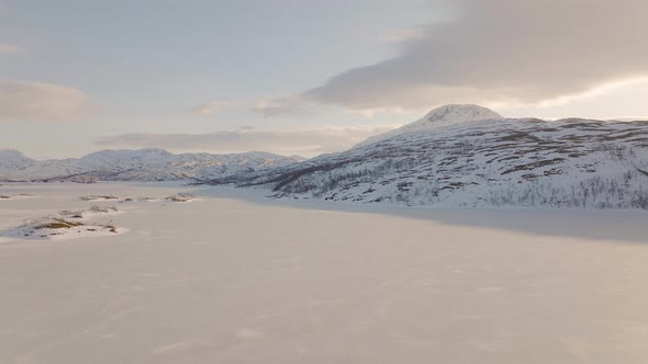 Drone tracks eagle in flight over snowy frozen lake; Ringvassoya, Norway alt