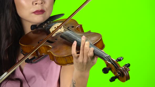 Girl Fingering the Strings Playing on a Brown Violin. Close Up. Green Screen alt