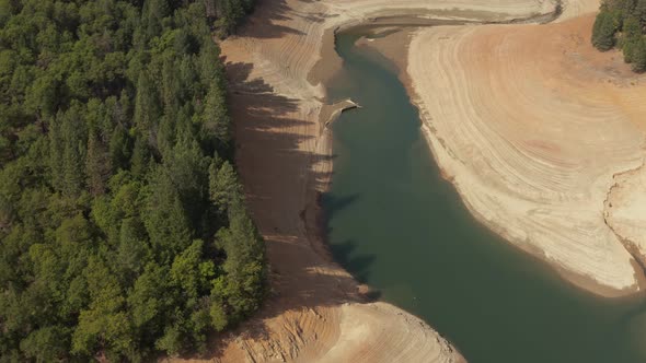 Aerial view of Shasta Lake rotating around trees looking at the water in Northern California low wat alt
