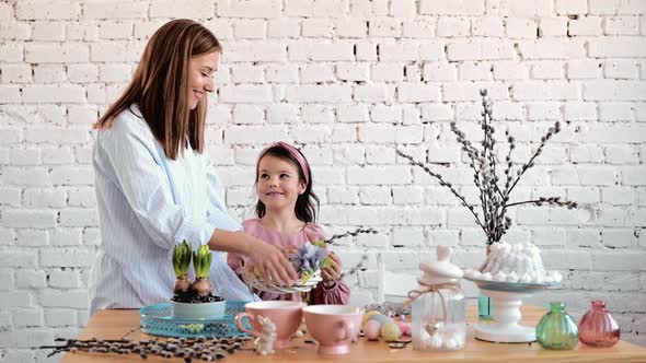 Young Woman and Child is Setting Easter Festive Table with Bunny and Eggs Decoration Wreath alt