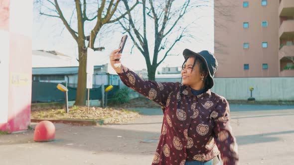 Young woman having a video call on her smartphone, making peace sign alt