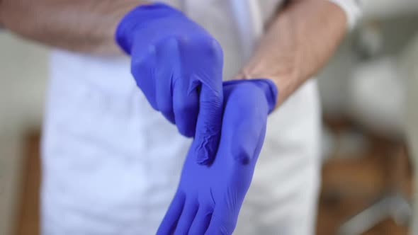 Male Surgeon Putting on Blue Medical Gloves Standing in Hospital Indoors alt