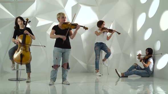 Musical String Quartet Girls Performs the Composition on Three Violins and Cello. White Studio alt