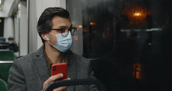 Handsome Man in Medical Mask and Glasses Using Smartphone alt