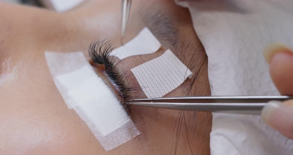 Female having eye lash extension in beauty salon alt