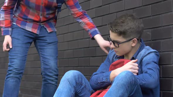 Teenage Student Giving Hand to Classmate, Supporting Humiliated Abuse Victim alt