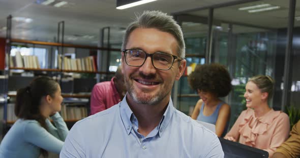 Portrait of caucasian businessman smiling over diverse business colleagues talking alt