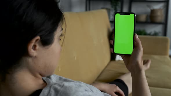 A Woman's Hand Holds A Smartphone With A Green Screen For Chromakey. Blank digital smartphone alt