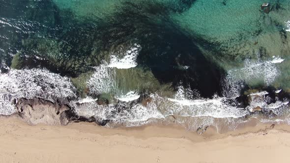 Top Aerial View of Sandy Coast with Foamy Transparent Waves Rolling In. Camera Moves Up From alt