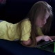 Cute small kid girl using tablet lying on sofa.