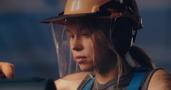 Focused Female Laborer in Protective Helmet Working on Heavy Equipment alt