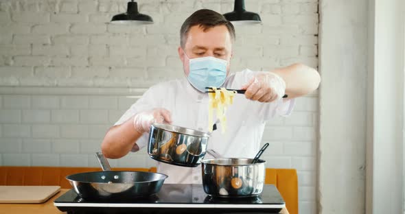 Chef cooker works with medical face mask in kitchen of cafe, restaurant alt