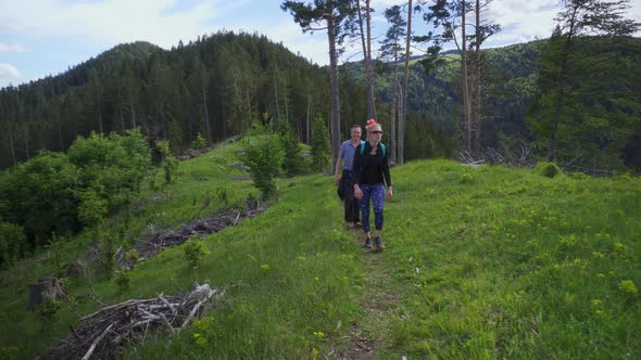 Happy Couple Hiking On Lush Green Hill On A Summer Holiday. - Medium Shot alt