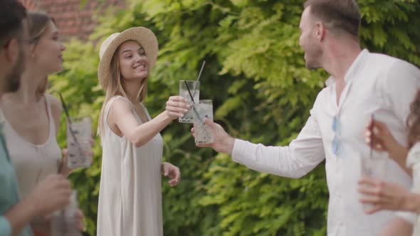 Group of happy young people cheering and having fun outdoors with drinks