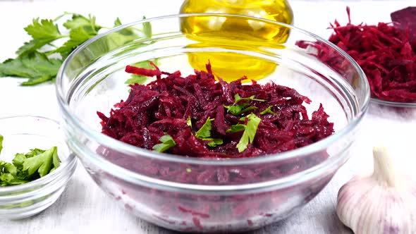A salad of grated beets in a salad bowl are sprinkled with the chopped parsley leaves