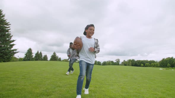 Excited Little Black Boy with American Football Running to Score Touchdown alt