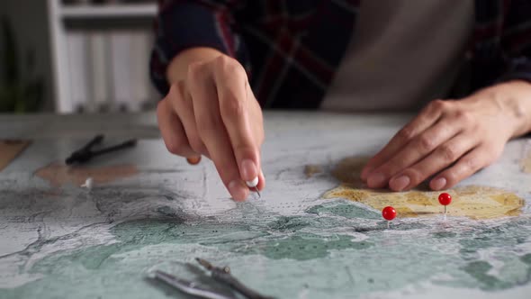 A Girl In Travel Clothes Sets A Pin And A Needle In A Map Planning A Long Awaited Trip While Waiting alt