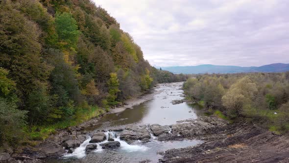Mountain river with cold clear water. The river flows over the stones with little waterfall. alt
