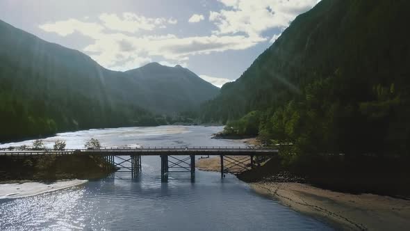 Drone camera shoots a bridge over a river between mountains with a dense forest (Montana, USA) alt