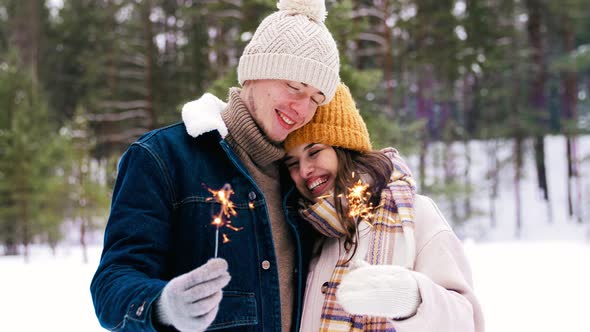 Happy Couple with Sparklers in Winter Forest