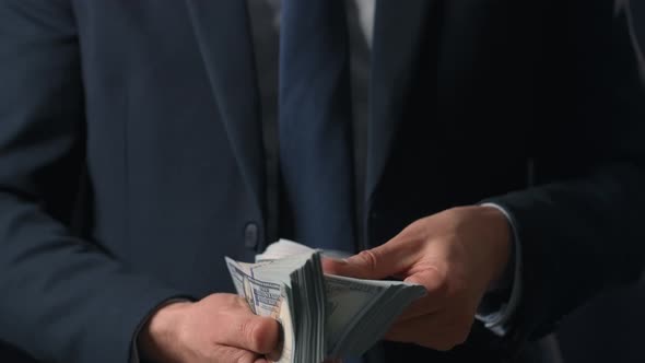 Formally Dressed Man Counting US Dollar Bills alt