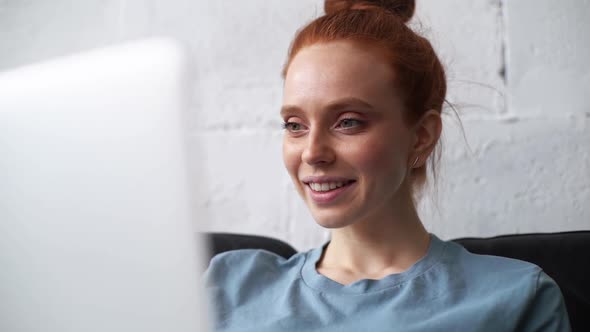 Close-up of Face of Redhead Young Businesswoman Working on Modern Laptop Computer. alt