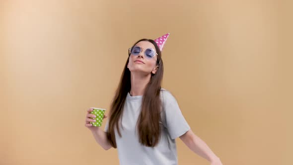 A Girl in Casual Clothes Dancing Wearing a Horn Hat Glasses and Holding a Glass alt