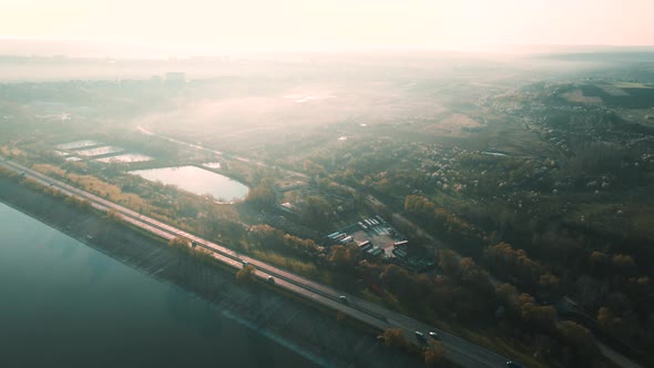 Aerial View of an Asphalt Road Between Agricultural Fields and a Lake alt
